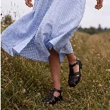 Sandalias de cuero vacuno color negro, estilo franciscana con tiras entrelazadas, cierre de hebilla metálica en el tobillo, suela de caucho y taco cuadrado.