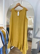 Vestido corto sin mangas color mostaza, de corte recto y holgado, con un pequeño volante en el ruedo.