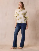 Blusa de gasa estampada con flores azules y violetas sobre fondo blanco, de manga 3/4 con volados.