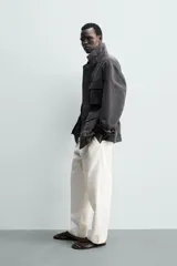 Cazadora relaxed fit de hombre, confeccionada en tejido técnico con algodón de color negro. Cuenta con cuello camisero, manga larga y bolsillos frontales de plastrón con solapa. Presenta cintura ajustable con cordón interior y cierre frontal con cremallera oculta por solapa con botones a presión.