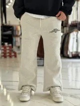 Pantalón de jogging oversize negro con felpa, de corte recto y cordón ajustable en la cintura. Presenta un pequeño estampado de texto blanco en el lateral izquierdo.