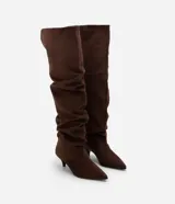 Bota over the knee color marrón, con acabado efecto gamuza y caída fruncida a lo largo de la caña. Presenta punta fina y tacón bajo y fino de 5 cm.