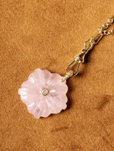 Collar con cadena de eslabones tipo bolita dorada y dije de piedra natural tallada en forma de flor con una pequeña circonia incrustada en el centro.