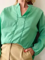 Blusa verde menta de corte holgado, con escote en V y detalle de puntilla en el escote y mangas largas con puños elásticos.