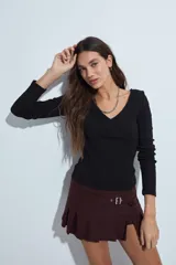 Remera de manga larga con escote cruzado en V, confeccionada en tejido elástico entallado al cuerpo.