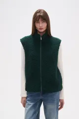 Chaleco sin mangas de textura peluche (teddy) color crema, con cuello alto y cierre frontal de cremallera.