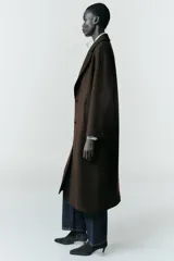 Abrigo largo de corte recto confeccionado en tejido con mezcla de lana, color marrón oscuro. Presenta cuello con solapas, cierre frontal con botones y bolsillos laterales de vivo.
