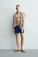 Short de baño azul con cintura elástica ajustable con cordón, bolsillos laterales y ribetes en contraste en los bordes.