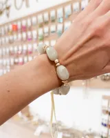 Pulsera elástica compuesta por piedras naturales de forma irregular en tono grisáceo verdoso, intercaladas con pequeñas cuentas metálicas doradas.