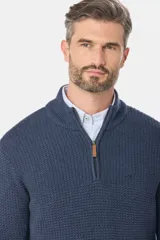 Buzo tejido de punto con textura, cuello alto y cierre frontal parcial. Presenta puños y ruedo acanalados, con un diseño clásico y versátil.