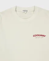 Camiseta color crema de algodón con cuello redondo y mangas cortas. Presenta un estampado pequeño con el logo de la marca en el frente.