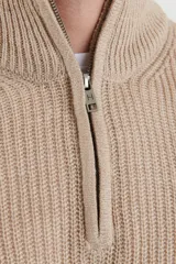 Sweater verde de punto inglés con cuello alto y cierre metálico frontal. Tiene mangas largas y terminaciones en punto canalé.