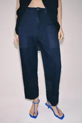 Pantalón worker de tiro medio de Zara Woman Collection, confeccionado en denim azul oscuro con detalles de combinación de tejidos a tono. Presenta cintura con trabillas, bolsillos laterales de plastrón, bajo acabado en vuelta y cierre frontal con cremallera y botón.