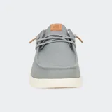 Zapatos de lona azul con detalles en cuero color suela en el talón y lengüeta. Presentan un diseño de estilo náutico con cordones elásticos, costuras reforzadas en la puntera y suela blanca de goma flexible.