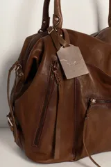 Bolso tote de cuero lavado negro con efecto gastado, interior amplio, bolsillos exteriores con cremallera, dos asas de mano y correa desmontable y regulable.