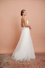 Vestido largo blanco de alta costura, con corset estructurado de tirantes finos con apliques florales y falda amplia de tul con brillo.