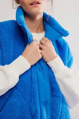 Chaleco de fleece color azul, de silueta oversized, con cierre frontal mediante botones a presión y bolsillos delanteros.