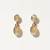 Par de aros colgantes con dos cuentas facetadas color beige unidas por un aro dorado.