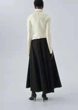 Falda larga de corte evasé en color negro, con cintura elástica y tiro medio. Presenta un diseño fluido y minimalista con bolsillos laterales ocultos.