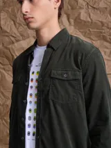 Camisa de pana color azul marino, con mangas largas, cuello clásico y dos bolsillos frontales con solapa y botón.