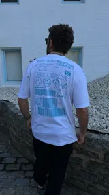 Remera blanca de algodón con estampado celeste en la espalda con diseño de ticket de envío con texto, códigos de barras, dibujos y la frase "Have a good day".