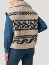 Chaleco de polar con diseño jacquard de motivos geométricos en tonos beige y gris oscuro. Presenta cuello alto, cierre frontal metálico con bordes de cuero sintético y bolsillos laterales con cierre.