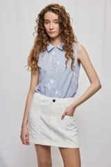 Falda de denim blanca de corte recto con bolsillos delanteros aplicados, costuras pespunteadas a contratono y cierre frontal con botón y cremallera.