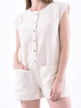 Monoprenda (romper) de color rojo, sin mangas, con cuello redondo y cierre frontal de botones. Presenta bolsillos delanteros a la altura de la cadera y un corte holgado.