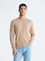 Sweater de punto color beige melange, de manga larga y cuello redondo, con un pequeño monograma bordado en el pecho.
