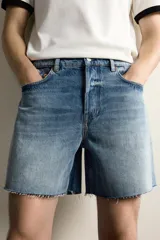 Shorts de denim de algodón con ajuste regular, diseño de cinco bolsillos y efecto lavado. Presenta cierre frontal con cremallera y botón, con el bajo acabado en corte irregular.