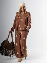 Conjunto de camisa y pantalón marrón chocolate con bordados en hilo crudo. El pantalón lleva elástico en la cintura.