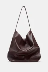 Bolso formato saca color marrón oscuro, confeccionado en piel. Tiene doble compartimento interior, asa de hombro y bolsillo interior con cierre mediante cremallera.