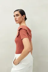 Top blanco tejido en punto acanalado con cuello amplio que se abre hacia los hombros y mangas cortas. Ajustado al cuerpo.