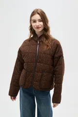 Campera acolchada de algodón con estampado animal print de leopardo en tonos marrones. Presenta cuello alto, cierre frontal, mangas largas y dos bolsillos frontales con ribetes oscuros.