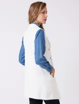 Chaleco largo tejido color blanco de la marca Sioni, con cuello solapa, doble botonadura dorada en el frente y bolsillos aplicados.