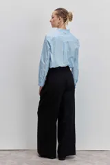 Camisa de algodón color celeste, con cuello mao y puños con detalle de volados. Presenta cierre frontal oculto con botones y un diseño de corte clásico.