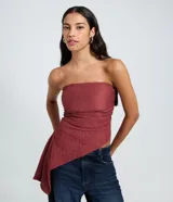 Blusa palabra de honor confeccionada en tul texturizado de color bordó, con fruncidos laterales y diseño asimétrico en la parte inferior.