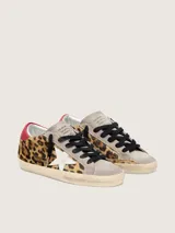 Zapatilla de cuero vacuno con pelo de potro y estampado animal print, combinada con gamuza en la puntera y lengüeta. Presenta una estrella lateral de cuero blanco, detalle de cuero rojo en el talón, cordones oscuros y suela con efecto envejecido.