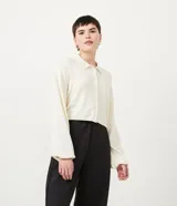 Cárdigan color crema de punto con cuello camisero, manga larga abullonada, cierre frontal abotonado y bolsillo de parche en el pecho.