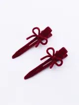 Set de dos pinzas para el pelo de color bordó, con acabado aterciopelado y detalle de lazo decorativo en la parte superior.