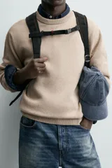 Sweater de punto color beige, de corte regular fit, con cuello redondo y manga larga. Presenta terminaciones en rib en cuello, puños y dobladillo.