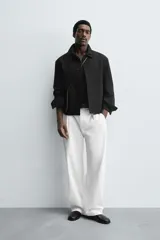 Sobrecamisa color beige de corte cuadrado, con cuello solapa, manga larga con puños abotonados, bolsillos laterales y cierre frontal con botones.