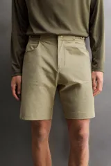 Pantalón corto de estilo técnico, color beige, con ajuste regular. Cuenta con cintura ajustable mediante cinturón de doble hebilla, cierre frontal con cremallera y botón a presión, bolsillos laterales y bolsillos con cremallera oculta.