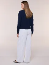 Camperita liviana de corte recto y acabado crepé color blanco, con cuello camisero clásico y cierre frontal de botones metálicos dorados. Presenta bolsillos en el pecho con solapa y mangas largas con puños abotonados.