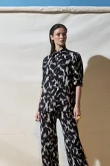 Camisa de viscosa crepe con estampado abstracto en blanco y negro, cuello camisero, mangas cortas abullonadas y cierre frontal con botones.