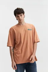 Remera verde esmeralda de manga corta con calce oversize, cuello redondo y estampado frontal con texto en azul.