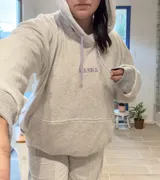 Canguro deportivo de tela suave con logo bordado, diseño holgado y mangas largas.