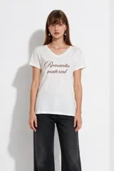 Remera de algodón blanca de manga corta, con cuello en V y estampa frontal con la frase "Romantic material" en color marrón.