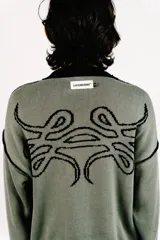 Sweater reversible de tejido de punto con diseño gráfico estilo tribal. Un lado presenta base negra con detalles en gris, mientras que el otro lado presenta base gris con detalles en negro. Posee cuello redondo, mangas largas y puños acanalados.