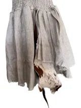 Vestido corto negro con corpiño fruncido y cuello alto con volantes. La falda tiene una caída irregular con aplicaciones de cuero y pelo en tonos blancos y negros.